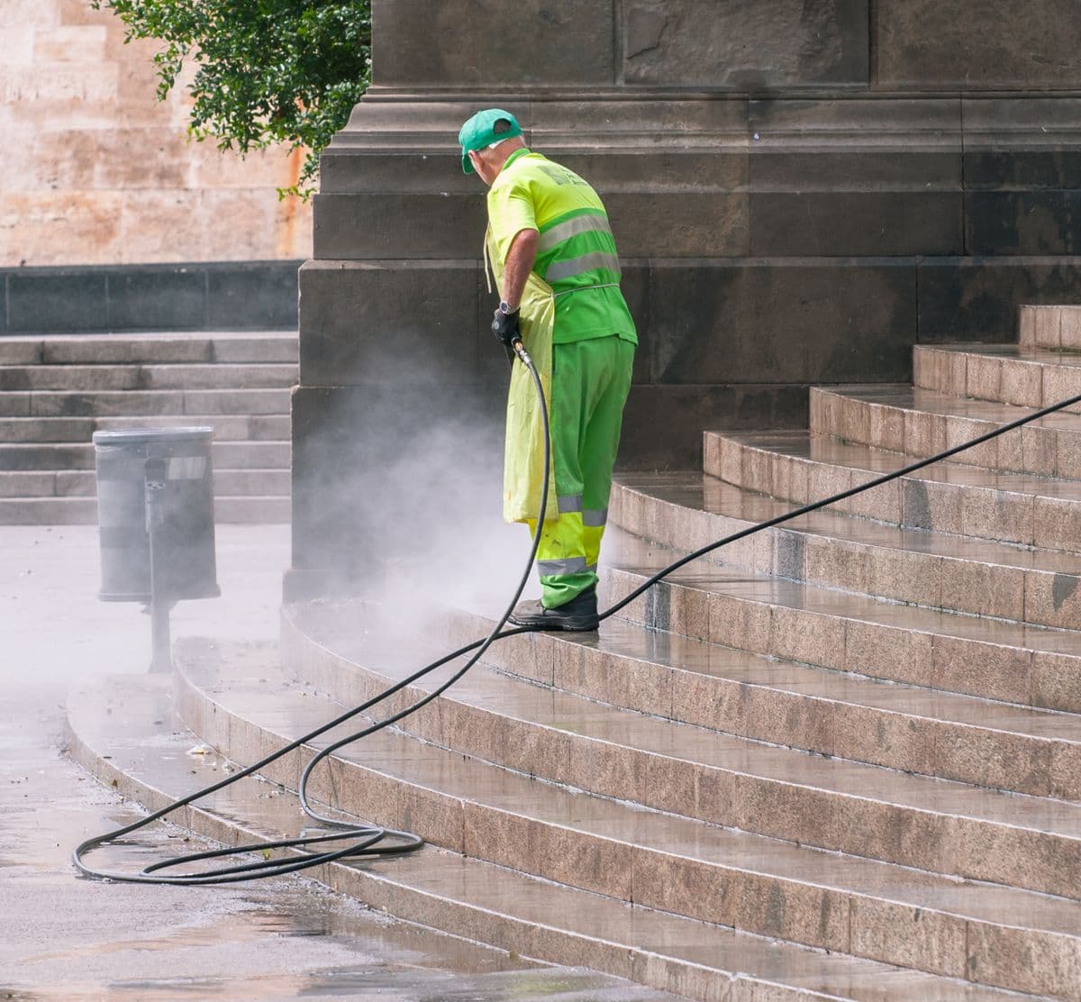 Worker pressure washing stone steps